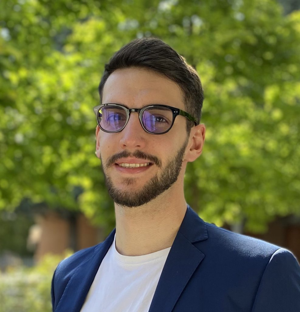 Smiling man with glasses, brown eyes, and short hair and bread